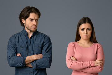 Young man looking with offence to his girlfriend after their quarrel, couple having relationship problems, light studio background with free space