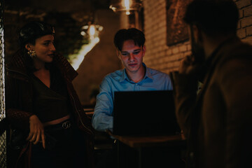 A focused business person works late at night in a cozy coffee bar, surrounded by colleagues in a warm, intimate atmosphere. The dim lighting adds to the relaxed and productive setting.
