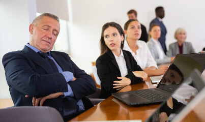 Mature businessman fell asleep at a business meeting in the negotiation room