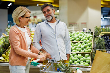Fototapeta premium Senior couple choosing fruits and vegetables at grocery store