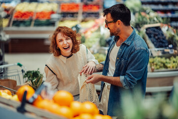 Happy couple laughing while shopping for groceries at the supermarket