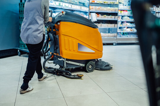 Janitor cleaning supermarket floor with a scrubber dryer machine