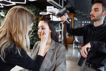 Stylists preparing a model with makeup and hair in a modern salon setting