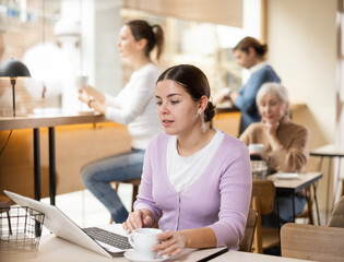 Confident female cafe customer enjoying peace and quiet while working on laptop