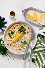 Squid rings in sour cream sauce in a white frying pan in a  frying pan.top view