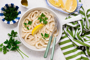 Squid rings in sour cream sauce in a white frying pan in a  frying pan.top view