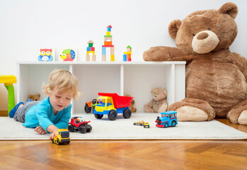 Sweet happy child boy having fun playing with colorful toys on the floor, at home