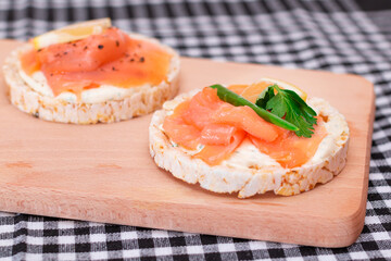 Rice Cake Sandwiches with Fresh Salmon, Cucumber, Lemon and Greens on Wooden Cutting Board. Diet Food. Quick and Healthy Sandwiches. Crispbread with Fresh Fillings. Healthy Dietary Snacks