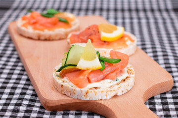 Rice Cake Sandwiches with Fresh Salmon, Cucumber, Lemon and Greens on Wooden Cutting Board. Diet Food. Quick and Healthy Sandwiches. Crispbread with Fresh Fillings. Healthy Dietary Snacks