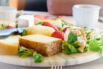 beautifully arranged plate of cheese for a gourmet meal, brunch or  a light snack, with fresh salad and strawberries