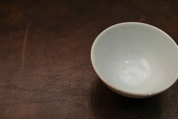 Overhead view of a mini white ceramic bowl on a brown background, Top view of a white ceramic mixing bowl, Flat lay of ceramic batter bowl