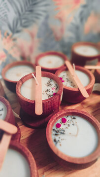 Velas de soja reci&eacute;n elaboradas en cuencos de madera con detalles de flores rojizas