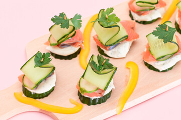 Canapes without Bread with Fresh Salmon, Cucumber and Cream Cheese on Wooden Cutting Board. Easy Breakfast. Diet Food. Quick and Healthy Sandwiches. Healthy Snacks with Tasty Fillings