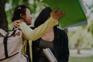 Multicultural students engage in collaborative learning outdoors in a park setting, working together on school projects after classes, suggesting teamwork and educational diversity.