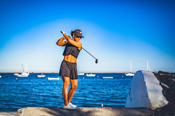 girl playing golf on the algarve beach