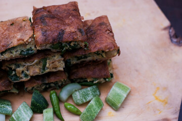 Indonesian Street Food Martabak Telur on the wooden cutting board, with Served pickles, Savory pan-fried pastry stuffed with egg, meat, green onion and spices.