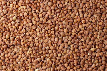 Dry Uncooked Brown Buckwheat Groats Background - Top View, Flat Lay. Raw Large Buckwheat Grains. Russian, Ukrainian and Belarusian Culture
