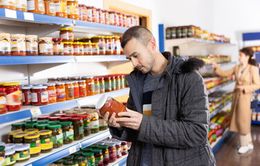 Adult man buyer in casual clothes chooses lecho in store