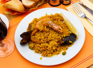 Classic dish of Spain, chicken and seafood paella in traditional pan top view.