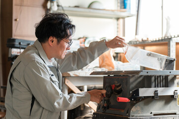 Obraz premium 丸鋸・昇降盤を使う作業着姿の中年男性 