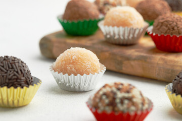 Typical Brazilian sweet brigadeiro. Assorted flavors of candies on a wooden board on the white table