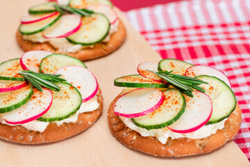 Light Breakfast or Diet Eating - Crispy Cracker Sandwich with Cream Cheese, Fresh Cucumber and Radish on Wooden Cooking Board on Magenta Background
