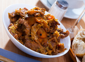 Appetizing cabbage stewed with pork meat and carrots on white plate..