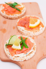 Rice Cake Sandwiches with Fresh Salmon, Cucumber, Lemon and Greens on Wooden Cutting Board. Diet Food. Quick and Healthy Sandwiches. Crispbread with Fresh Fillings. Healthy Dietary Snacks