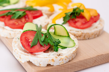 Different Vegan Rice Cake Sandwiches with Fresh Tomato, Yellow Paprika and Greens on Wooden Cutting Board. Vegetarian Diet Food. Quick and Healthy Sandwiches. Crispbread with Fresh Fillings