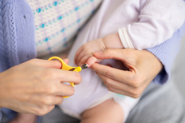 Mother carefully trimming her baby nail with scissors