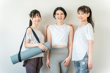 Obraz premium スポーツジムでヨガウェアを着てトレーニングする女性達（ヨガ・ホットヨガ・エクササイズ） 