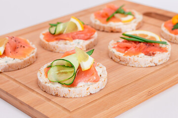 Rice Cake Sandwiches with Fresh Salmon, Cucumber, Lemon and Greens on Bamboo Cutting Board. Diet Food. Quick and Healthy Sandwiches. Crispbread with Fresh Fillings. Healthy Dietary Snacks