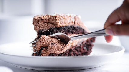 Chocolate cake with fork on white plate. Selective focus.