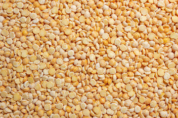 Uncooked Polished Split Peas Background. A Culinary Canvas of Dry Yellow Peas, Creating a Lively and Textured Background for Gourmet Cooking. Scattered Raw Polished Peas. Healthy Eating Ingredients
