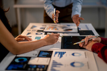 Three people are sitting at a table with papers and pens, working on a project