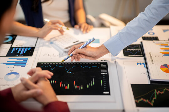 A man is pointing at a graph on a table while two other people look on