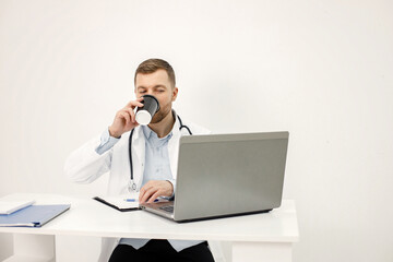 Caucasian doctor sitting at workplace and using laptop