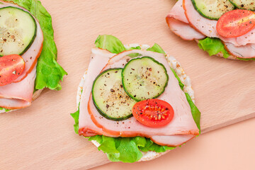 Light Breakfast. Quick and Healthy Sandwiches. Rice Cakes with Ham, Tomato, Fresh Cucumber and Green Salad on Wooden Cutting Board. Beige Background