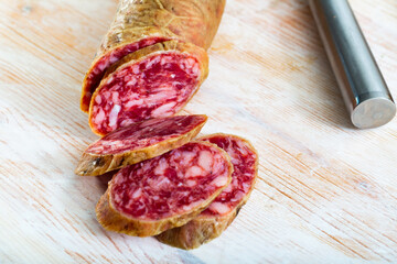 Popular Spanish salchichon sausage sliced on wooden background