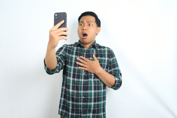 asian man shocked while looking at smartphone, touching chest, isolated on white background