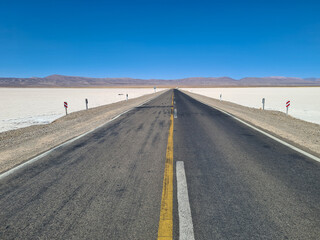 Asphalted highway crossing a dry salt-covered lake