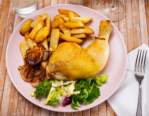 Appetizing chicken leg quarter served with garnish of baked potatoes, browned onions and fresh leafy vegetable salad