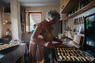 An elderly woman prepares delicious pastries in a warm, inviting kitchen. The scene captures the essence of home cooking and the joy of creating homemade treats.