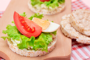 Rice Cake Sandwiches with Tomato, Lettuce and Egg on Wooden Cutting Board. Easy Breakfast. Diet Food. Quick and Healthy Sandwiches. Crispbread with Tasty Filling. Healthy Dietary Snack