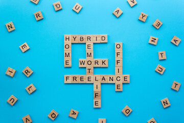 Remote work crossword puzzle made of wooden blocks with letters on a blue background. Selective...