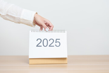 Business woman hand change 2025 Year Calendar on table in office background. countdown, Happy New Year, Resolution, Year End and New Start and Goals Plan Action Concept