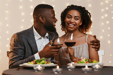 Young afro man and woman having dinner in restaurant, drinking wine, celebrating St. Valentine's Day