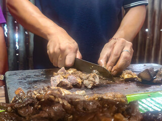 Description: A person is cutting a large piece of meat on a cutting board.