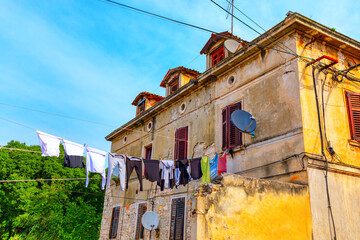 Building exterior featuring colorful clothes hanging on a line. Garments hanging on a clothesline,...