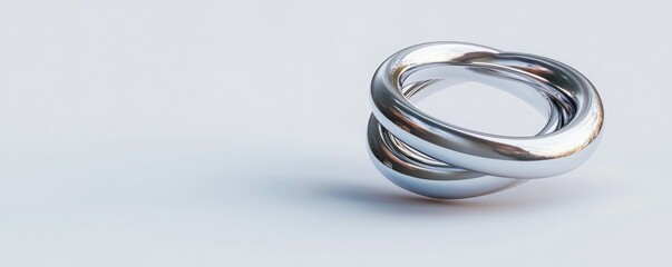 Fototapeta premium A polished, intertwined silver ring rests on a light surface, showcasing its elegant design and reflective qualities.